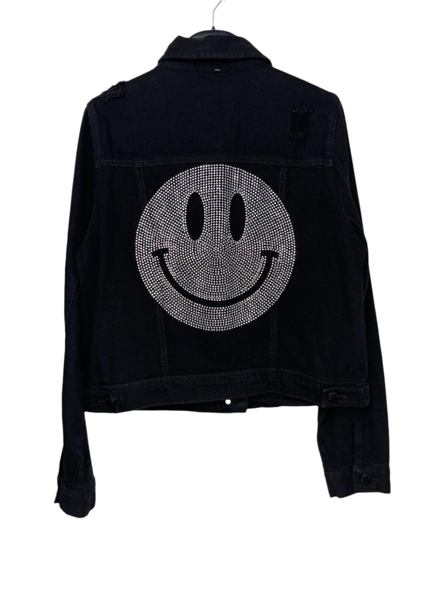 A black denim jacket with a crystal silver smiley design on the back, featuring a pointed collar, button front, and front flap pockets.